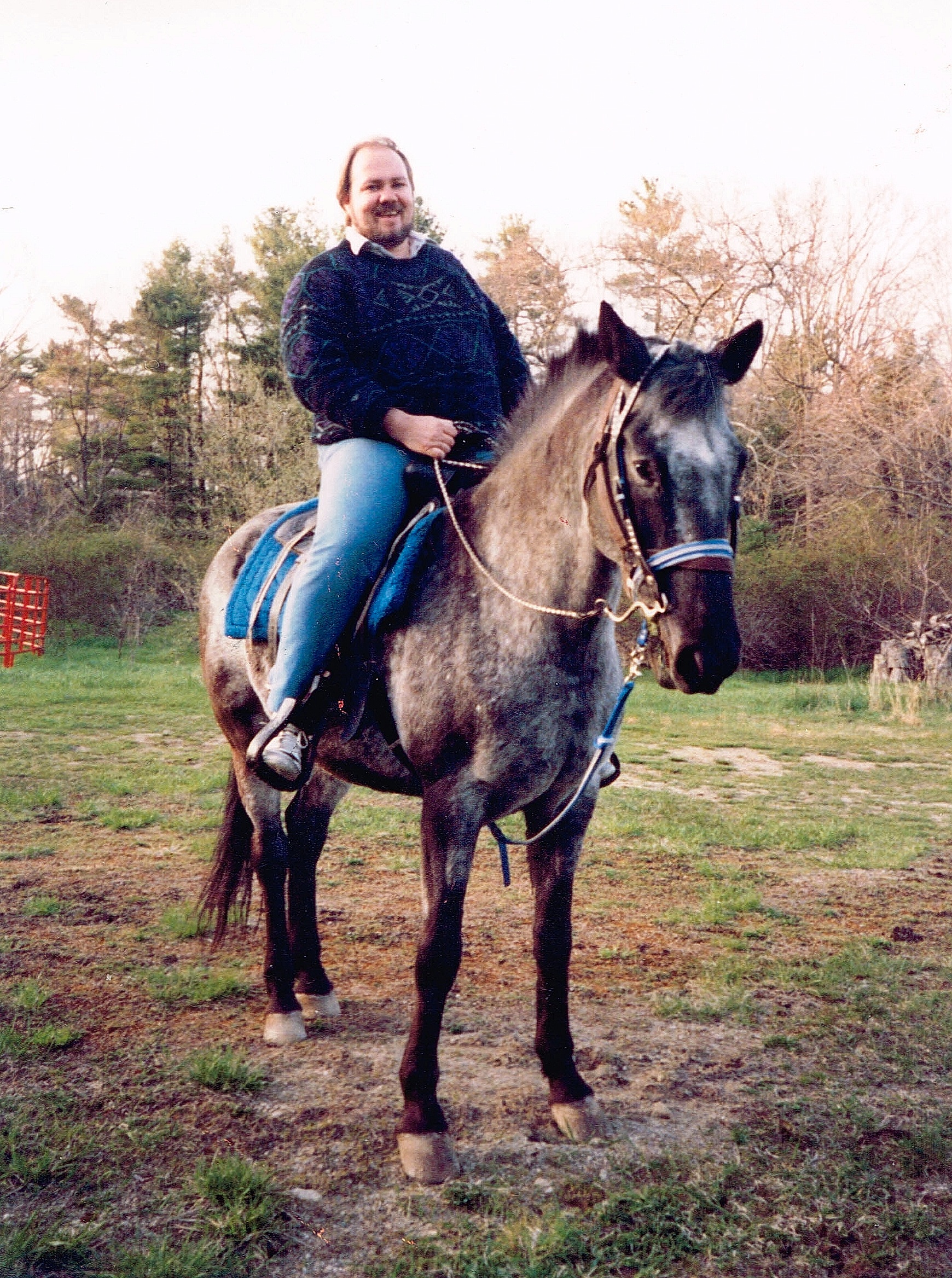 A younger Barrett astride a dapple gray horse in a New England field